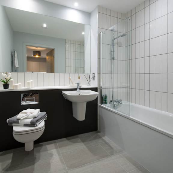 Thumbnail 5 of 5 A modern bathroom with a toilet, sink, and bathtub.