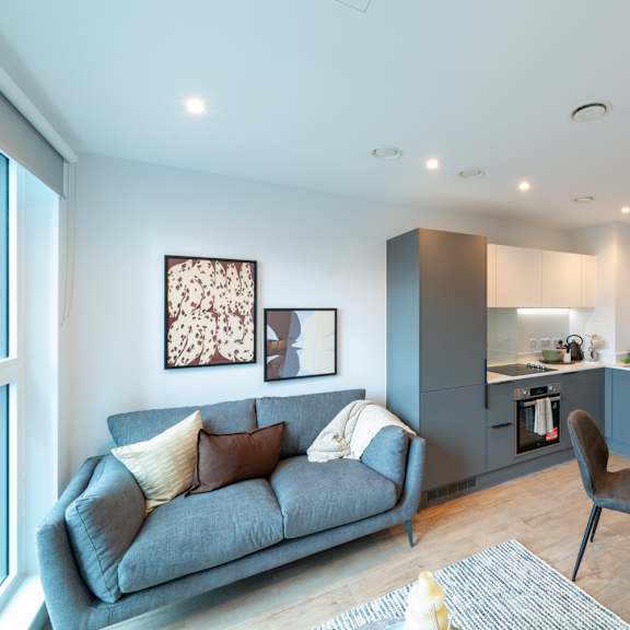 Thumbnail 4 of 11 A modern living room with a grey sofa and a round table.