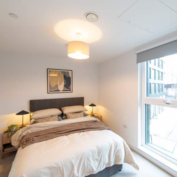 Thumbnail 6 of 11 A bedroom with a large bed and a window overlooking a cityscape.