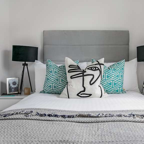 Thumbnail 2 of 5 a bedroom with a bed with two pillows and two nightstands with lamps