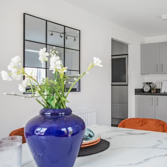 Thumbnail 3 of 5 a kitchen and dining area with a table and a vase of flowers