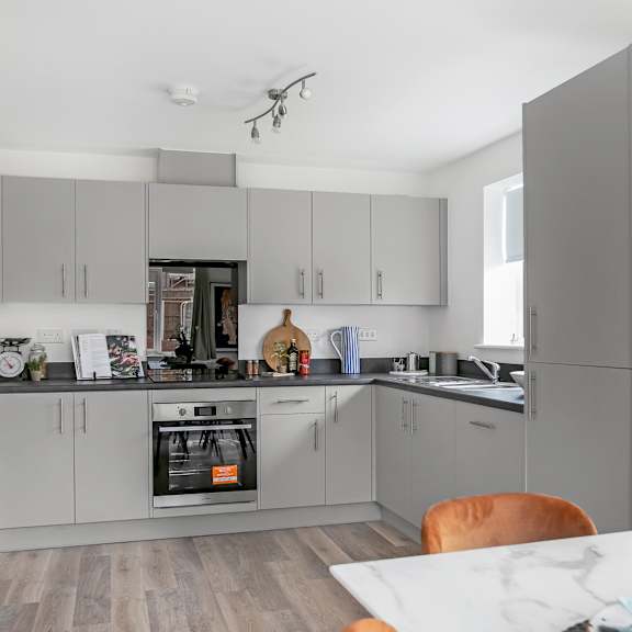 Thumbnail 1 of 5 a kitchen with gray cabinets and a table and a stove