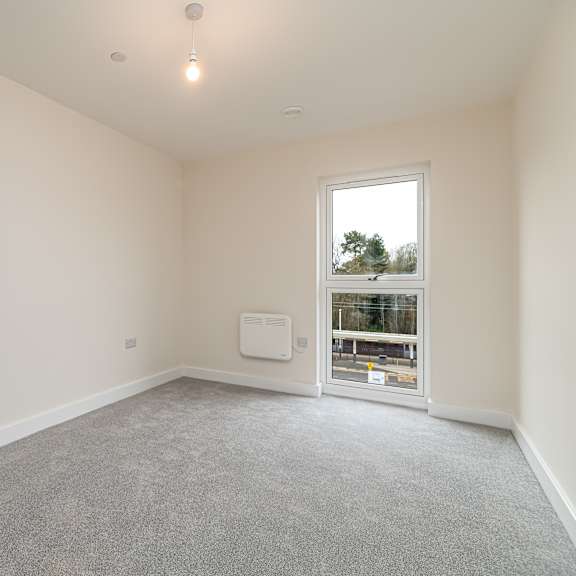 Thumbnail 2 of 12 A room with a window and a carpeted floor.