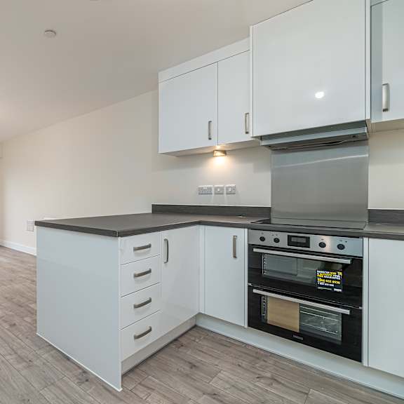 Thumbnail 5 of 12 A kitchen with white cabinets and a black countertop.