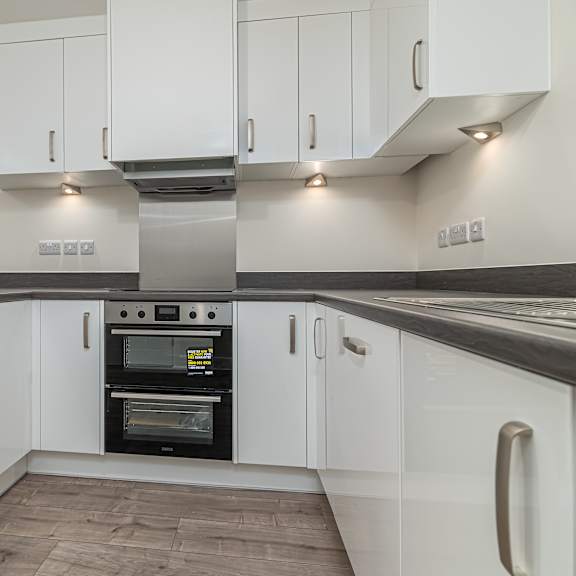Thumbnail 7 of 12 A modern kitchen with white cabinets and a stainless steel oven.