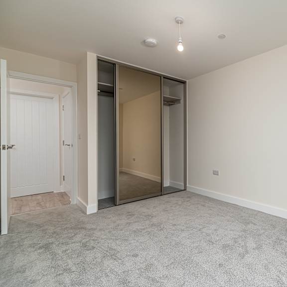 Thumbnail 1 of 12 A room with a carpeted floor and a white door.