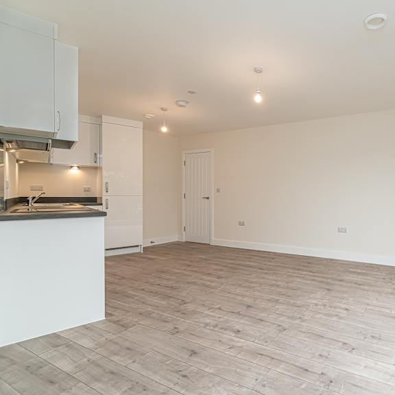 Thumbnail 5 of 9 A spacious room with wooden flooring and white walls.