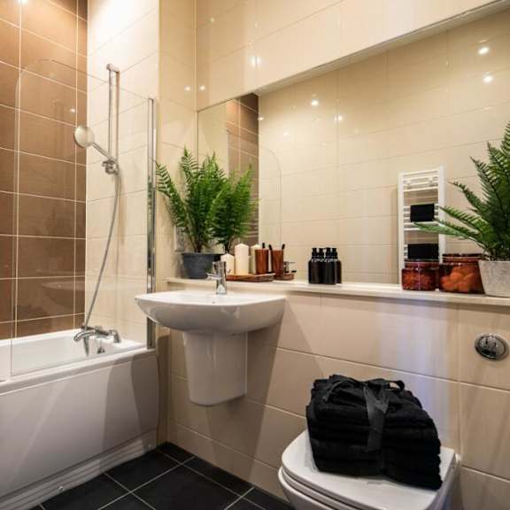 Thumbnail 2 of 3 A bathroom with a white tub, sink, and toilet at The Keel Apartments, Liverpool, L3 4GE