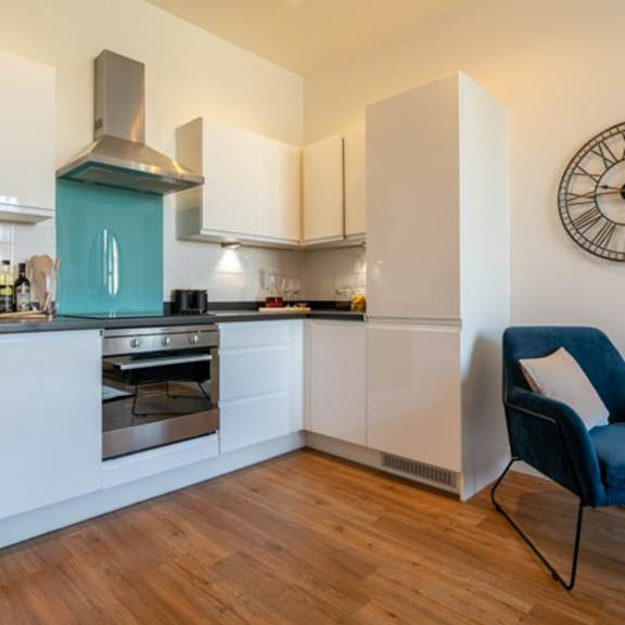 Thumbnail 4 of 6 a kitchen with a chair and a clock on the wall at The Keel Apartments, Liverpool