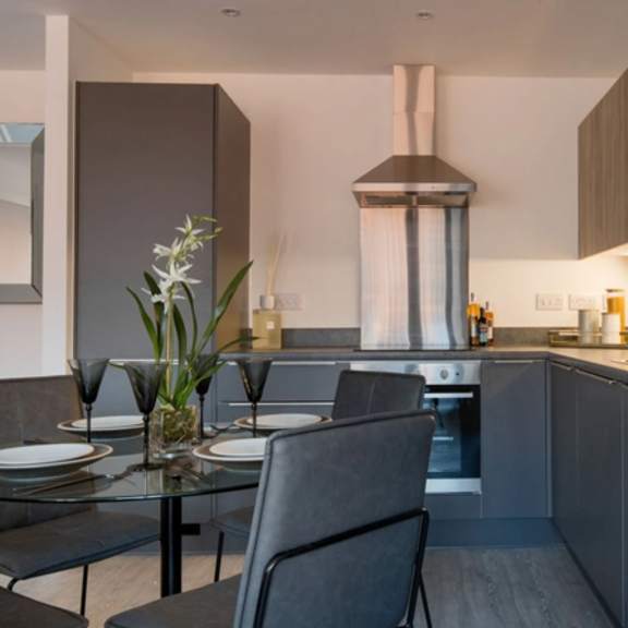 Thumbnail 3 of 5 a kitchen and dining room with a table and chairs at Vox Apartments, Manchester