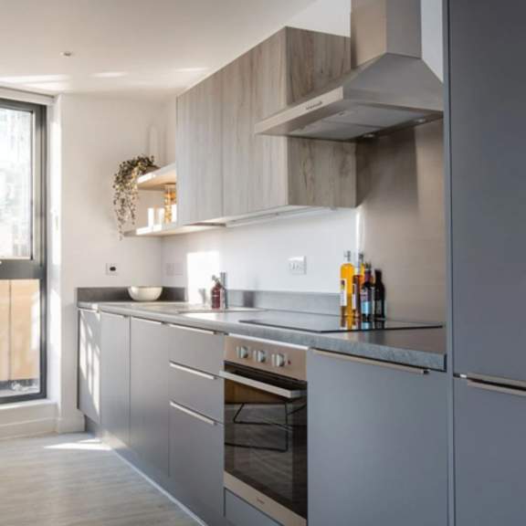 Thumbnail 6 of 8 a kitchen with gray cabinets and a yellow chair at Vox Apartments, Manchester