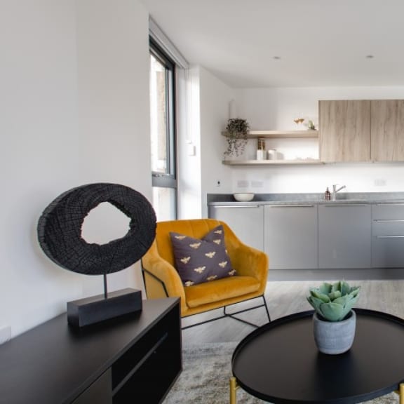 Thumbnail 4 of 8 a kitchen and living room with a green couch and yellow chairs at Vox Apartments, Manchester, M15 4YD
