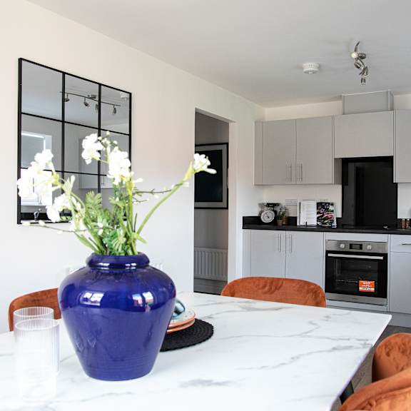 Thumbnail 3 of 5 a kitchen with white cabinets and a blue vase with flowers on a table