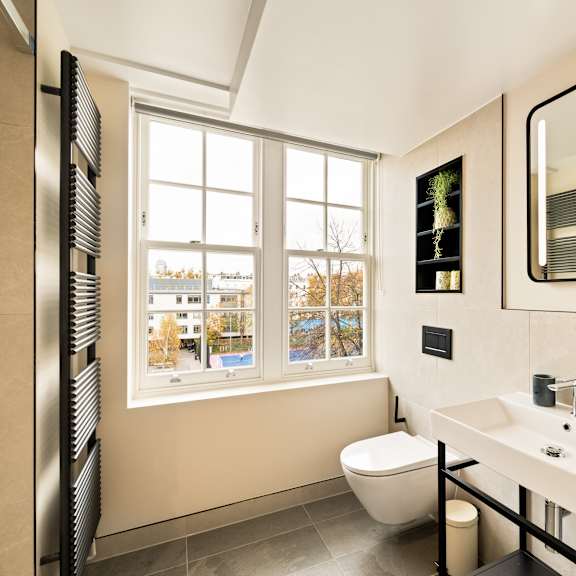 Thumbnail 4 of 4 A bathroom with a toilet, sink, and mirror.