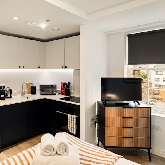 Thumbnail 2 of 4 A modern kitchen with black countertops and white cabinets.