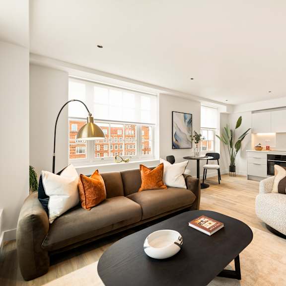 Thumbnail 1 of 4 A living room with a brown couch and a black coffee table.