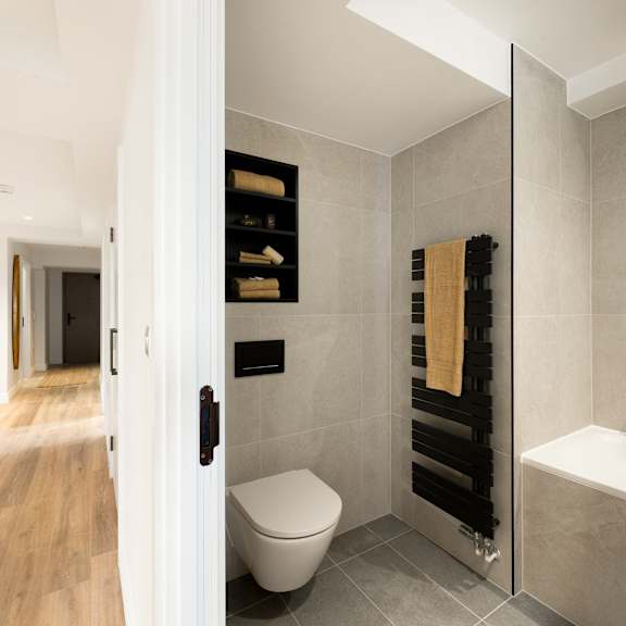 Thumbnail 6 of 6 A bathroom with a toilet, a towel rack, and a bathtub.