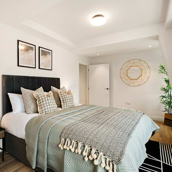 Thumbnail 3 of 6 A bedroom with a large bed and a wooden nightstand.