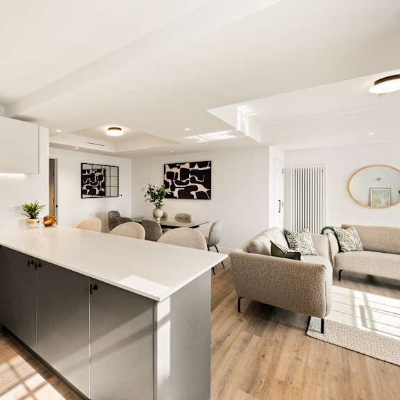 Thumbnail 2 of 6 A modern kitchen with a white countertop and grey cabinets.