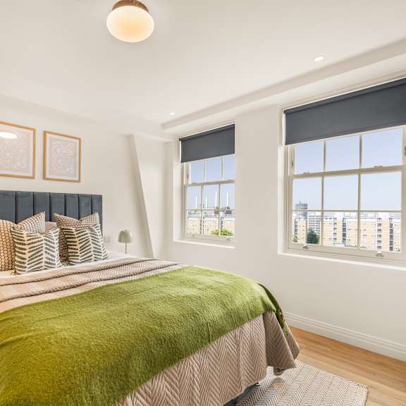 Thumbnail 3 of 5 A bedroom with a large bed and a window overlooking a cityscape.