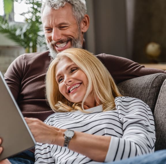 a couple sitting on a couch using a laptop computer