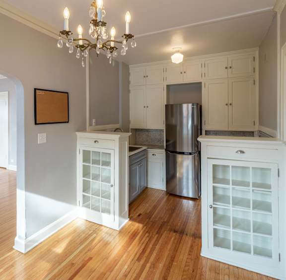 A kitchen with wooden floors and white cabinets.