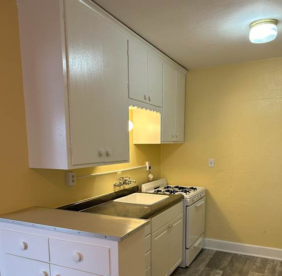 A kitchen with white cabinets and a yellow wall.