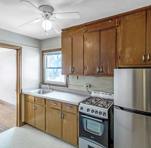 A kitchen with wooden cabinets and a stainless steel refrigerator.