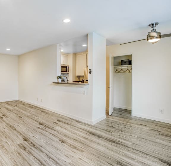 an empty living room with wood flooring and a kitchen