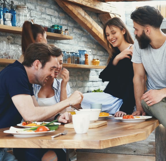 a group of people sitting around a table in a kitchen