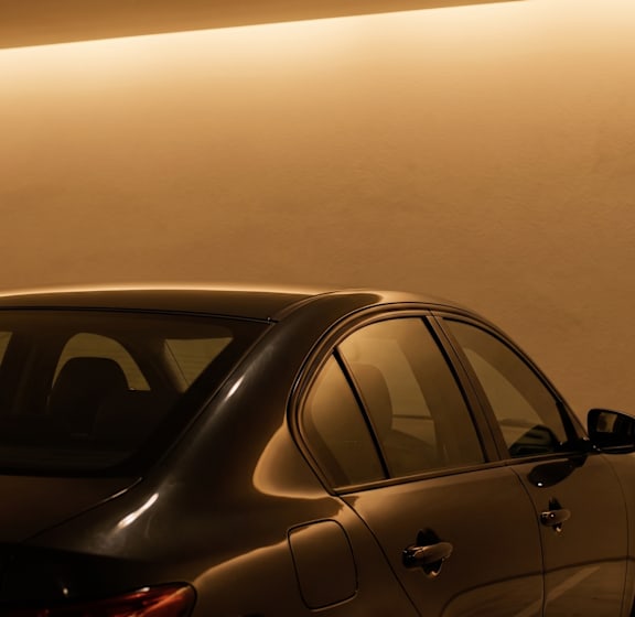 A car is parked in a room with a light-colored wall.