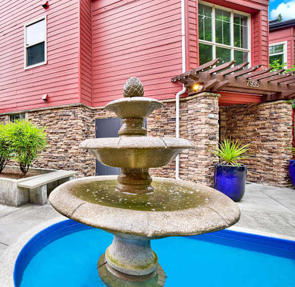 A fountain in the middle of a pool surrounded by a house.
