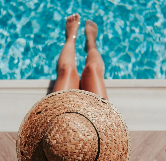 a woman with a straw hat laying by a pool