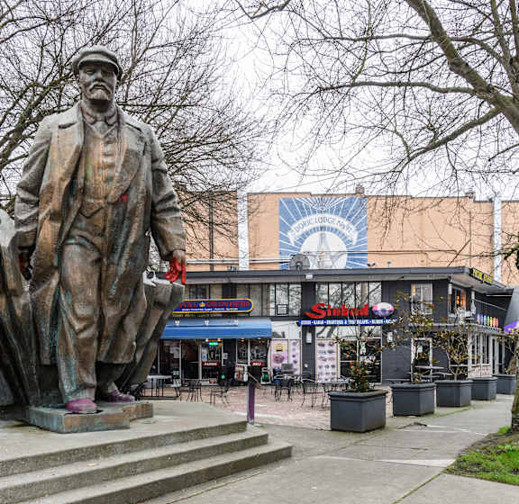 A statue of a man stands in front of a building with a sign that says "Stone.".