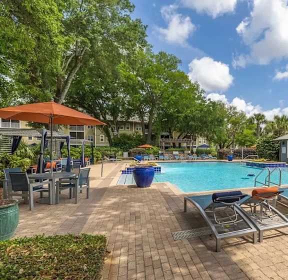 A pool area with sun loungers and a building in the background.