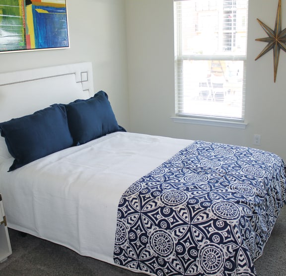 a bedroom with a white bed and a blue and white comforter