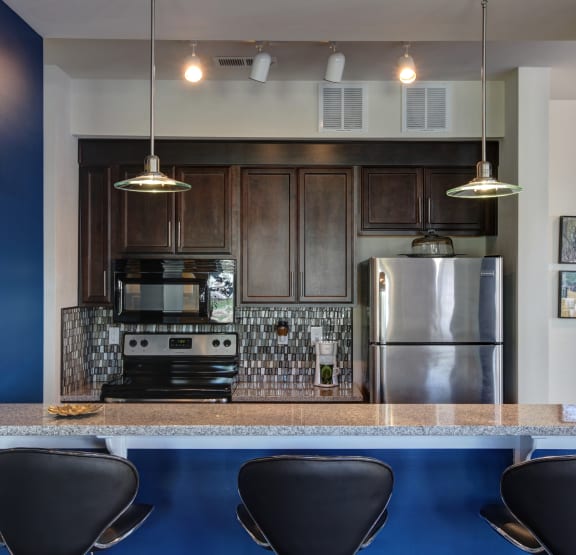 a kitchen with stainless steel appliances and a counter with four chairs