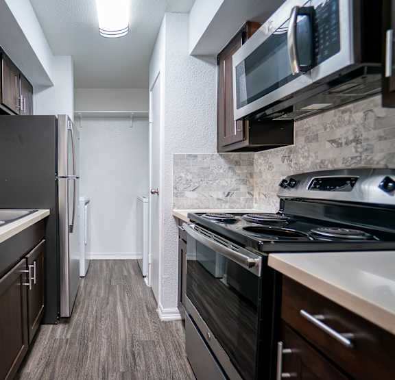 A kitchen with dark wood cabinets and stainless steel appliances.
