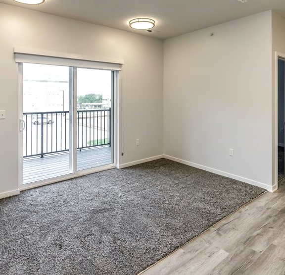 a bedroom with hardwood flooring and a sliding glass door leading to a balcony
