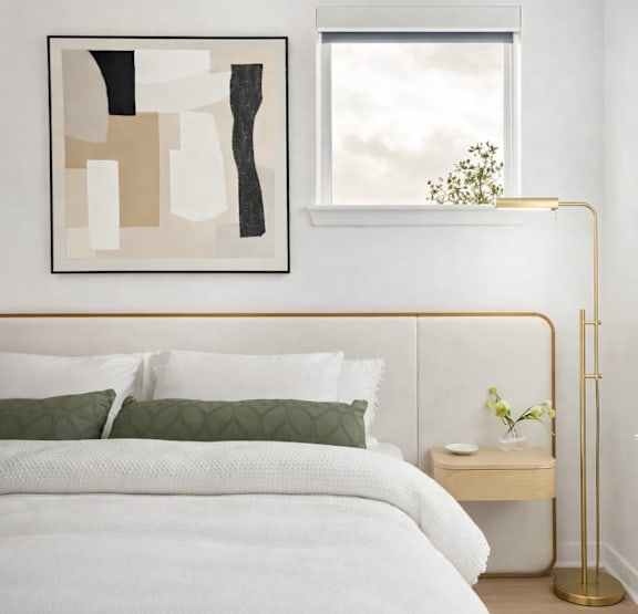 A bedroom with a white bed and a gold floor lamp.