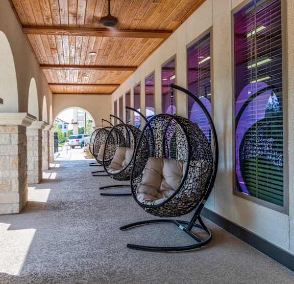 A row of hanging chairs are lined up on a carpeted walkway.