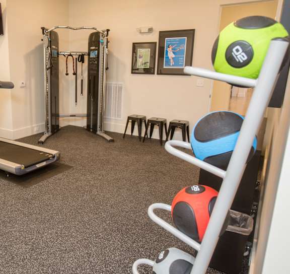 A gym room with a treadmill, exercise balls, and weights.