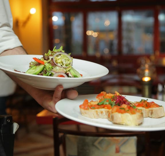 a waiter holding two plates of food in a restaurant