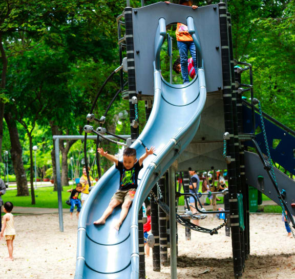 a boy sliding down a blue slide on a playground