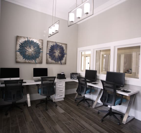 a computer room with desks and chairs and two paintings on the wall