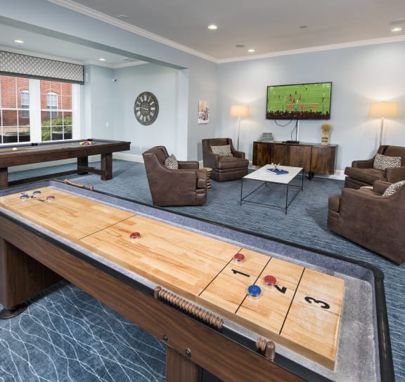a games room with a shuffleboard table and couches