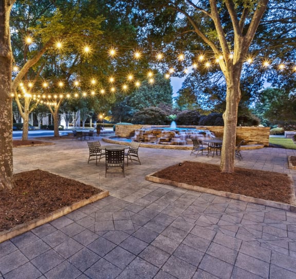 a patio with lights hanging from the trees