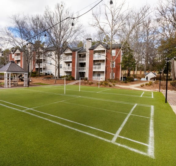 a tennis court at the resort with apartments in the background