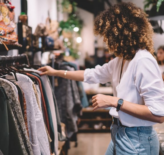 a woman looking at clothes on a rack in a clothing store