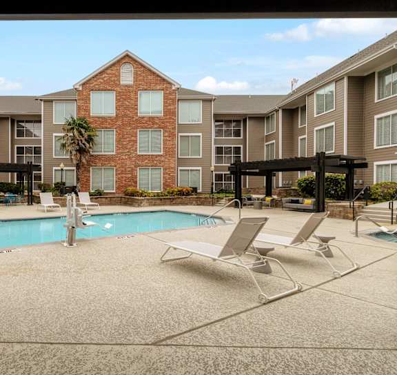 an apartment building with a swimming pool and chairs